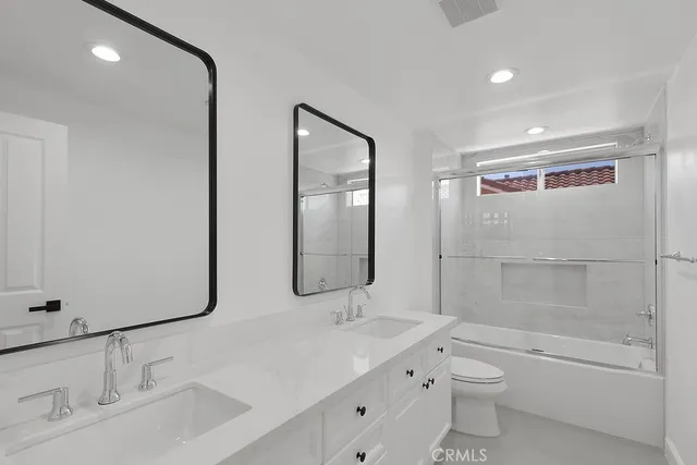 a bathroom with a double vanity sink toilet mirror and bathtub
