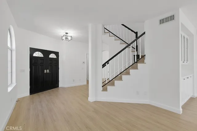 a view of an empty room with wooden floor and stairs