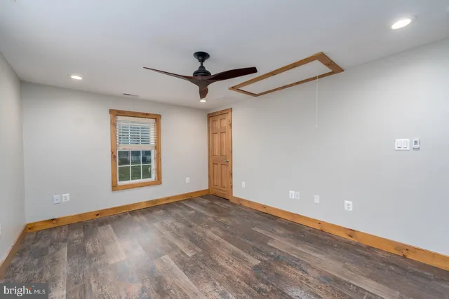 a view of an empty room with a window and wooden floor