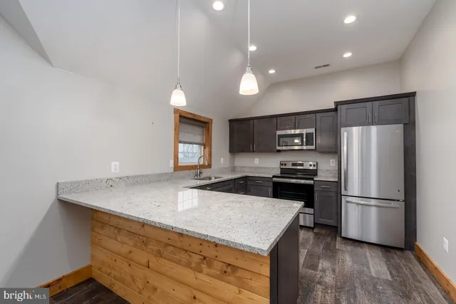 a kitchen with kitchen island a refrigerator stove a sink and a oven with wooden floor