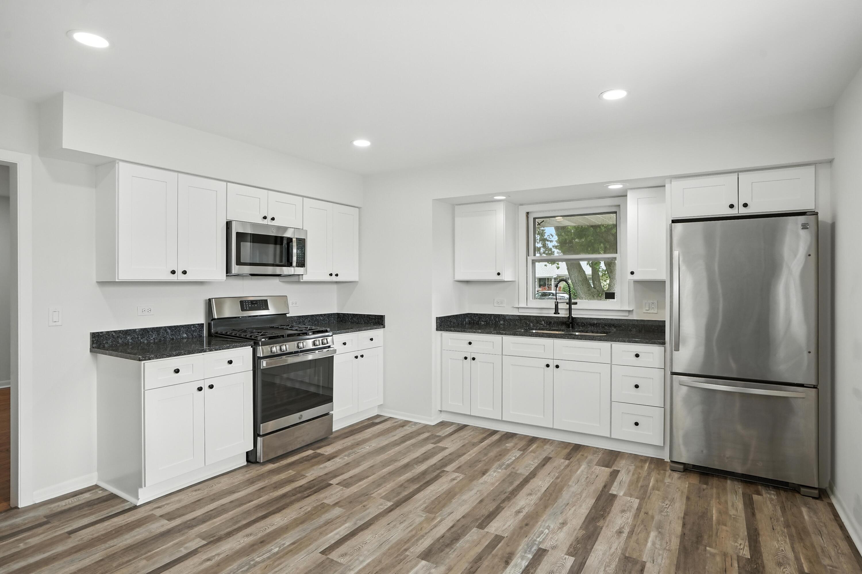 3312 East 170th Street Lansing, IL 60438 - Photo 9 of 38 a kitchen with granite countertop white cabinets white stainless steel appliances and wooden floors