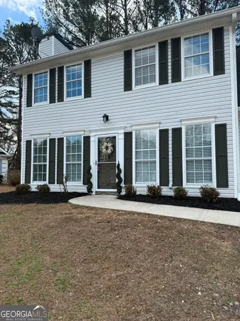 a view of a brick house with large windows and a yard