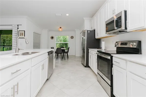 a kitchen with stainless steel appliances kitchen island granite countertop a refrigerator oven a sink dishwasher and white cabinets with wooden floor