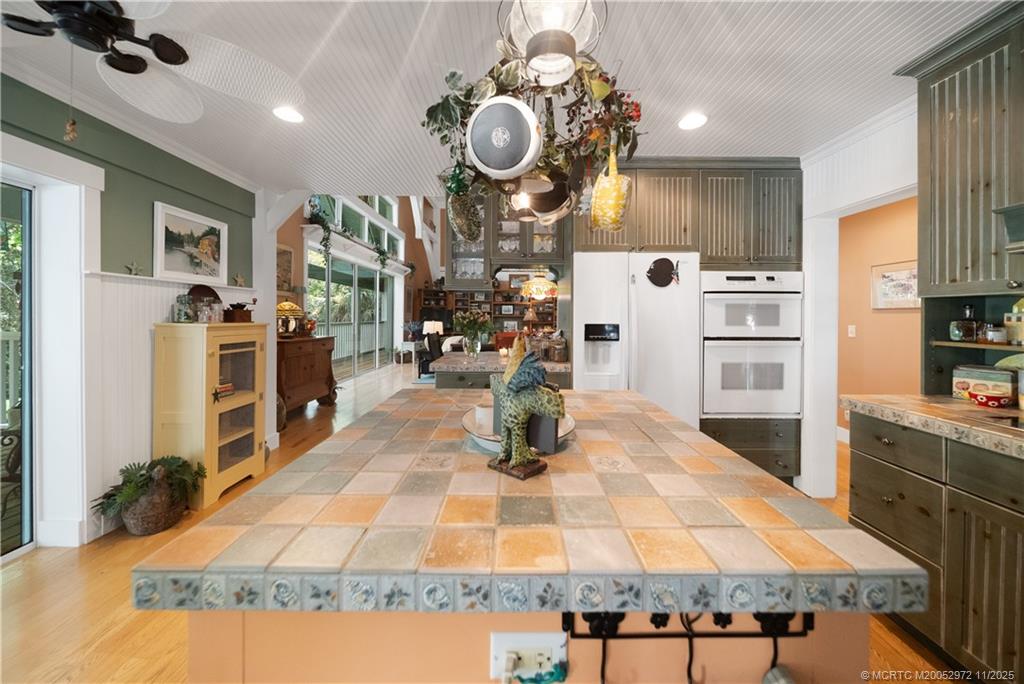 12 Oak Hill Way Stuart, FL 34996 - Photo 11 of 63 a kitchen with stainless steel appliances kitchen island granite countertop a refrigerator a stove top oven and couches with wooden floor