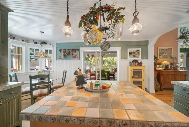 a large kitchen with stainless steel appliances kitchen island granite countertop a table chairs in it and a view of living room