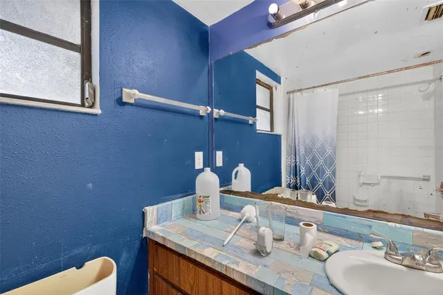 a bathroom with a granite countertop sink a mirror and shower