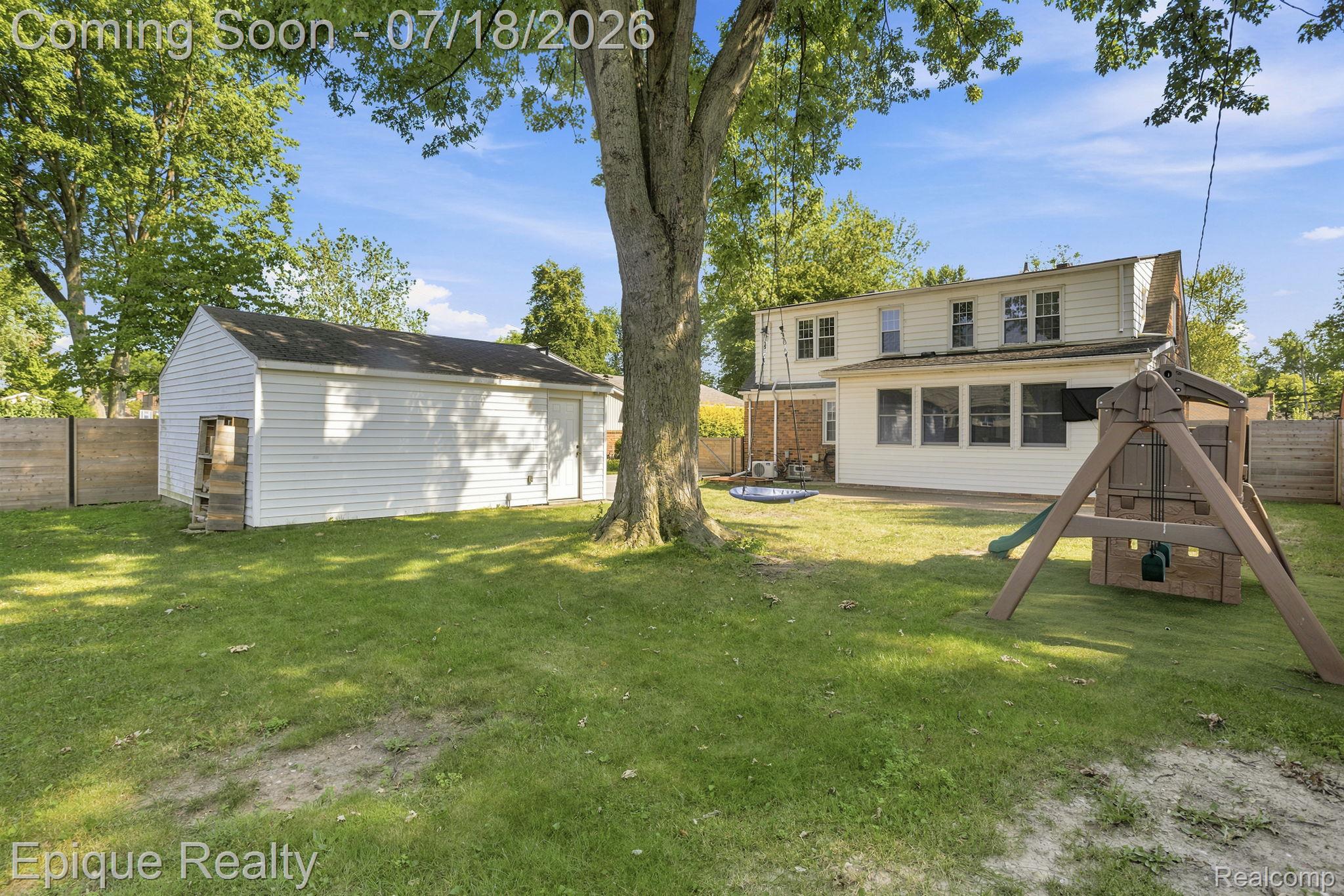 1206 Hawthorne Road Grosse Pointe, MI 48236 - Photo 26 of 28 Expansive backyard featuring a detached garage with white siding, mature trees, and a sunroom extension on the main dwelling