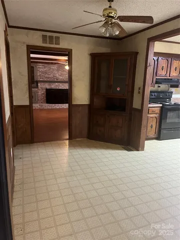 a view of an empty room with wooden floor and fan