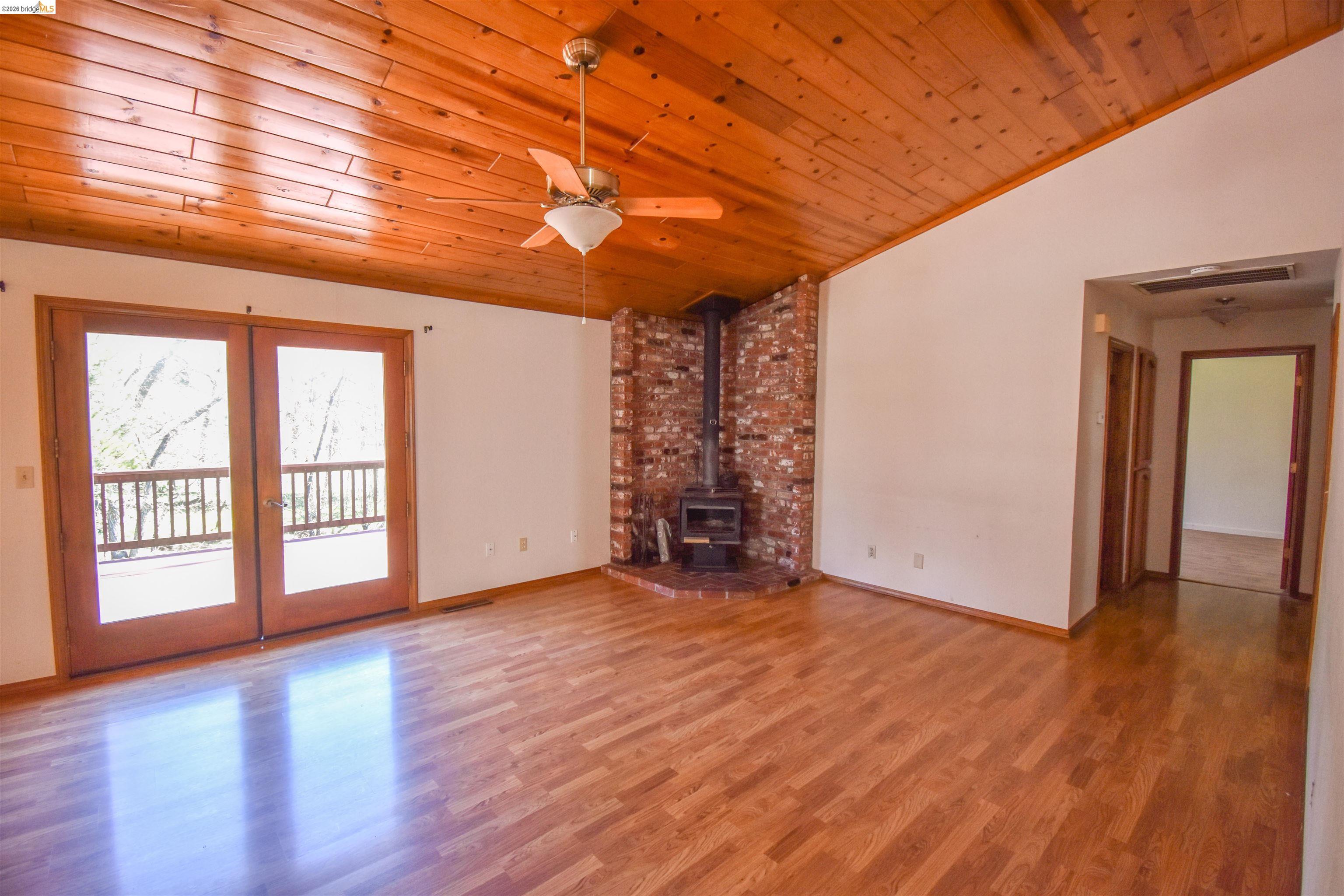 21515 Bellview Creek Road Sonora, CA 95370 - Photo 5 of 31 Unfurnished living room with ceiling fan, a vaulted wood ceiling, wood finished floors, and a wood stove