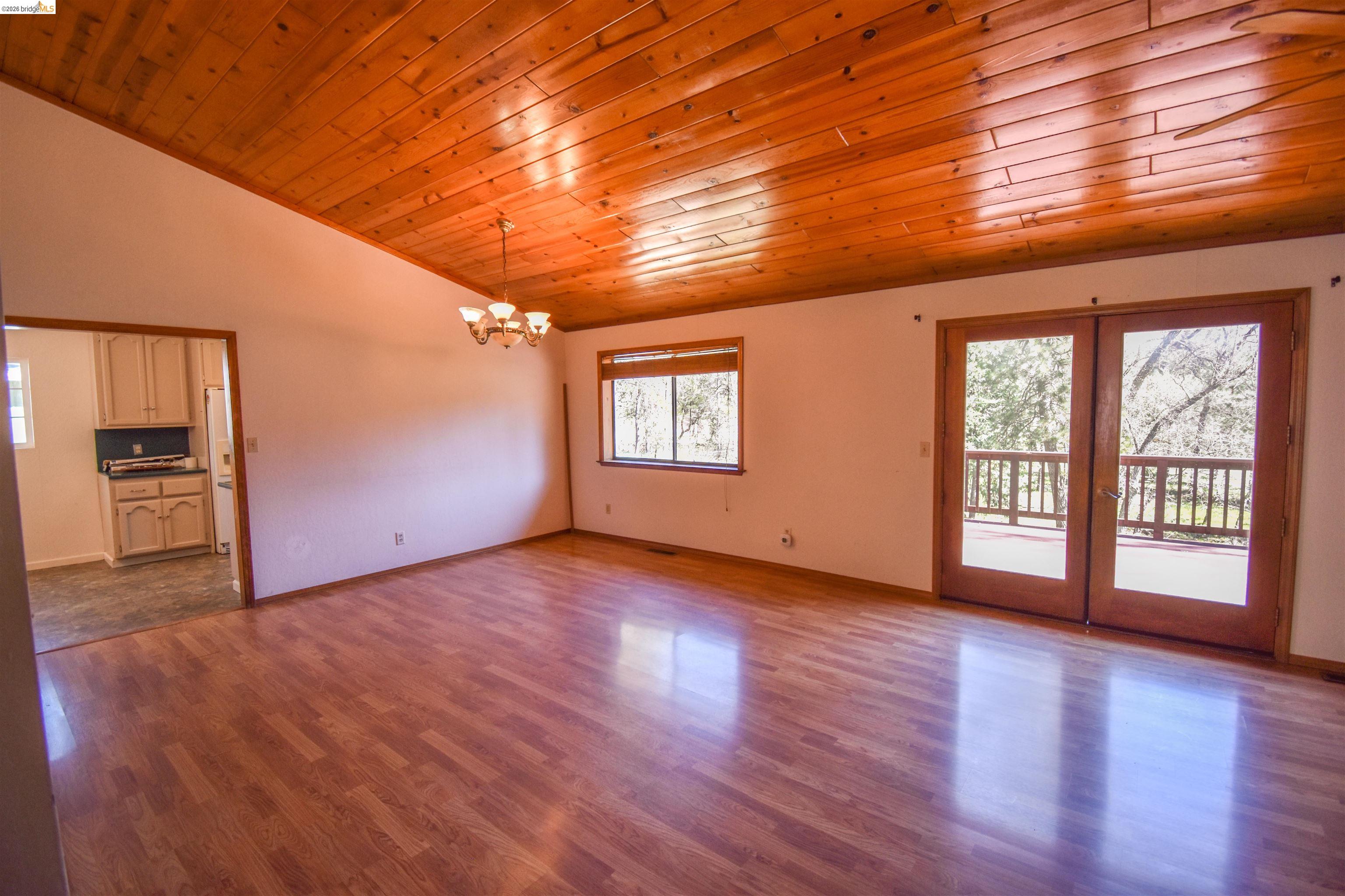 21515 Bellview Creek Road Sonora, CA 95370 - Photo 6 of 31 Unfurnished room featuring a vaulted wood ceiling, healthy amount of natural light, wood finished floors, a chandelier, and french doors