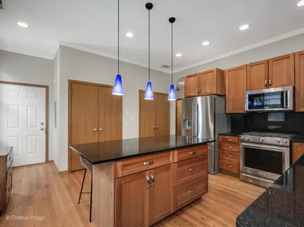 a kitchen with stainless steel appliances kitchen island granite countertop a refrigerator a oven and a wooden floors