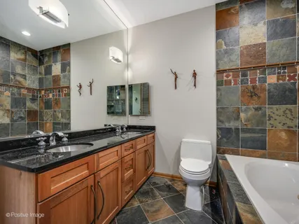 a spacious bathroom with a granite countertop sink a toilet a mirror and shower