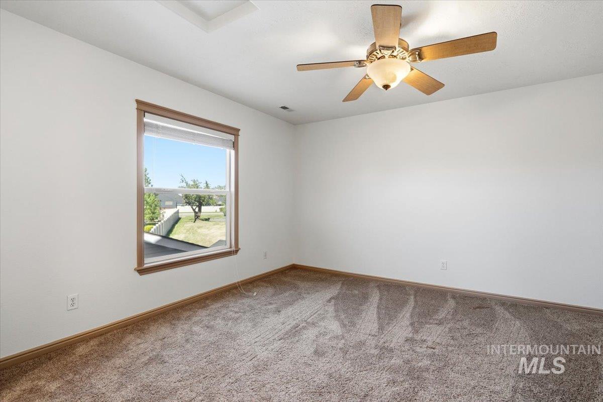 1183 North Buffalo Way Middleton, ID 83644 - Photo 30 of 47 Carpeted room featuring a ceiling fan with light fixture, a window with wood-finish trim, and white walls