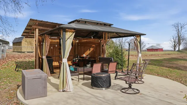 a view of a wooden house with large trees and playing area