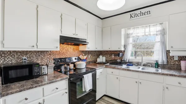 a kitchen with granite countertop white cabinets stainless steel appliances a sink and a window