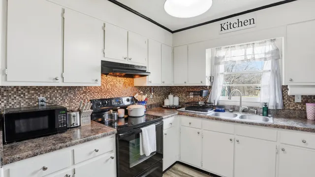 a kitchen with granite countertop white cabinets stainless steel appliances a sink and a window