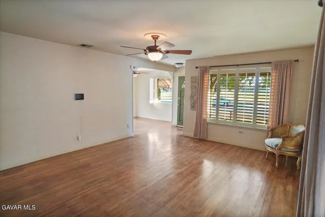 a view of an empty room with wooden floor and a window