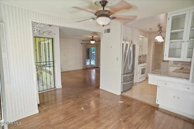 a view of a hallway with wooden floor and a kitchen