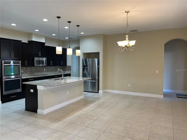 a large kitchen with a chandelier and stainless steel appliances