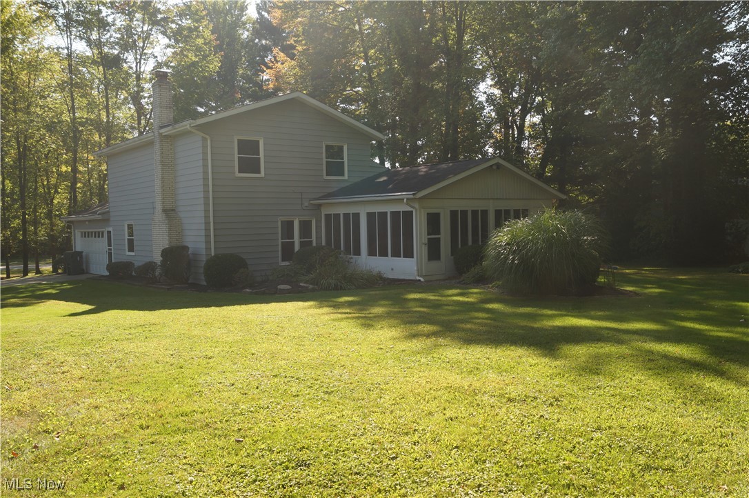 7372 Liberty Road Solon, OH 44139 - Photo 22 of 33 Rear view of property featuring a sunroom, a chimney, a lawn, and view of scattered trees