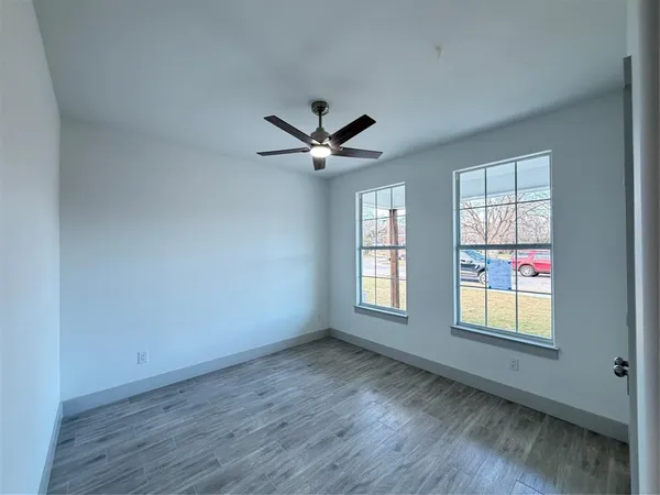 a view of an empty room with a window and wooden floor