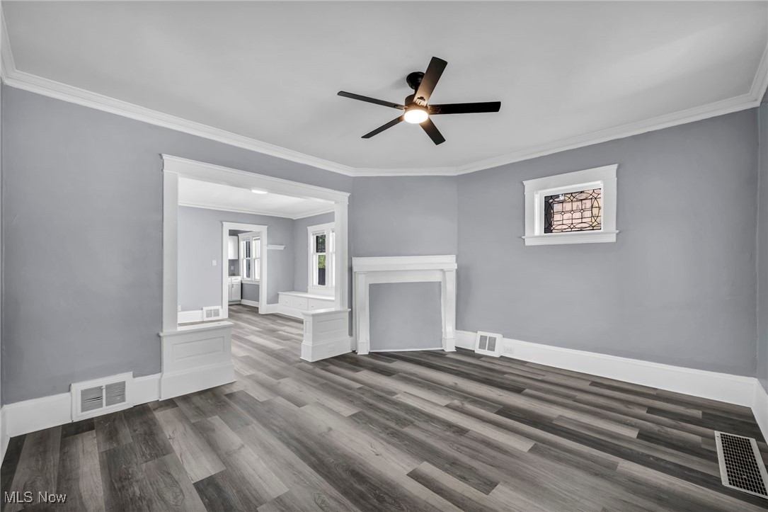 10112 Kinsman Road Cleveland, OH 44104 - Photo 15 of 49 Unfurnished living room with ornamental molding, dark wood-style flooring, plenty of natural light, and a ceiling fan