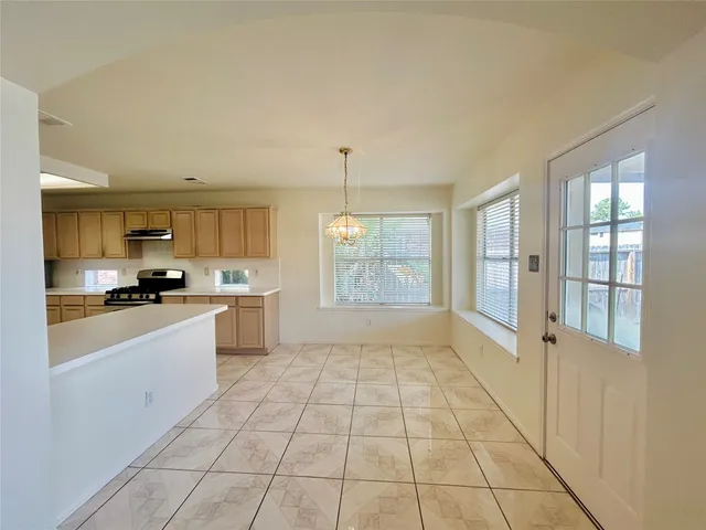 a large white kitchen with a stove a sink dishwasher and a refrigerator with white cabinets
