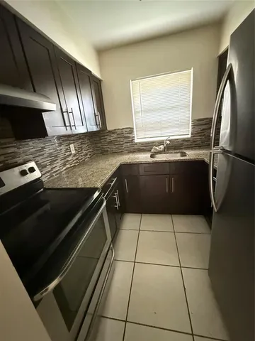 a kitchen with granite countertop a stove a sink and a refrigerator