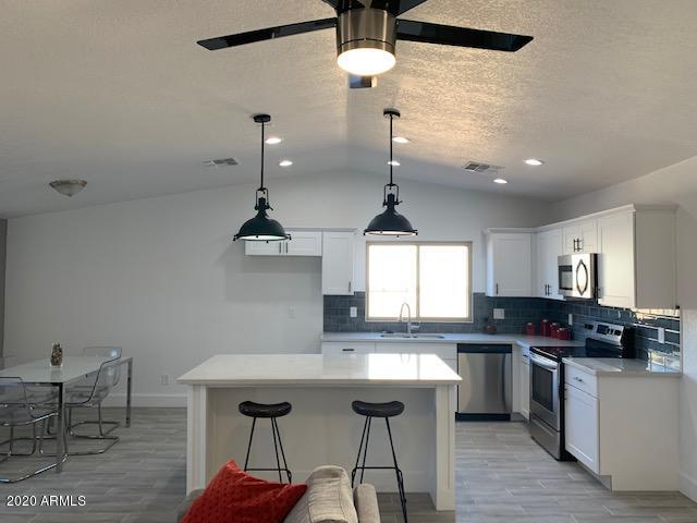 1706 West Colt Road Chandler, AZ 85224 - Photo 23 of 35 a kitchen with stainless steel appliances a dining table chairs and white cabinets