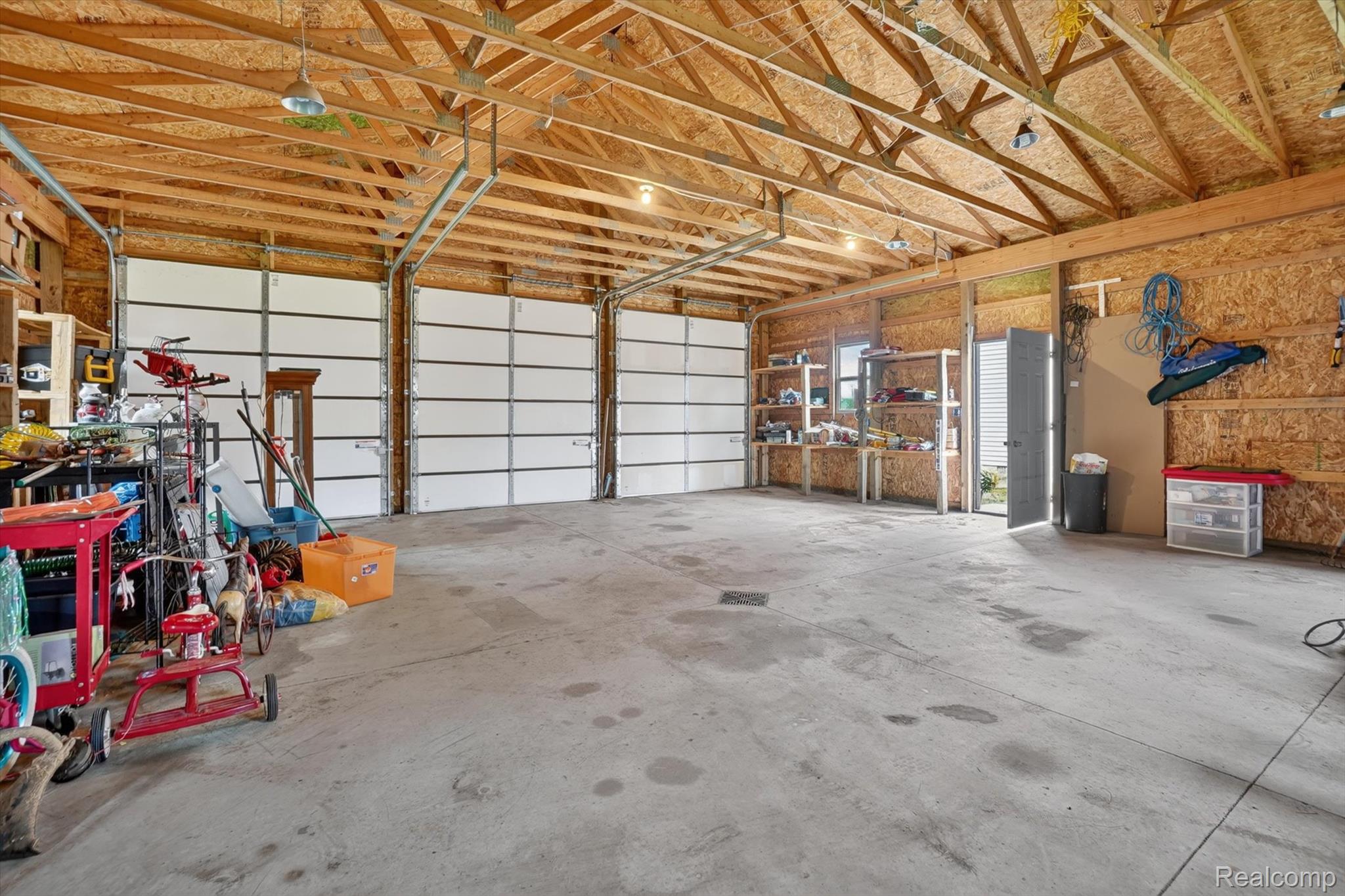 10977 Maple Road Birch Run, MI 48415 - Photo 35 of 49 Spacious garage with exposed wood beam ceiling, concrete flooring, and multiple garage doors