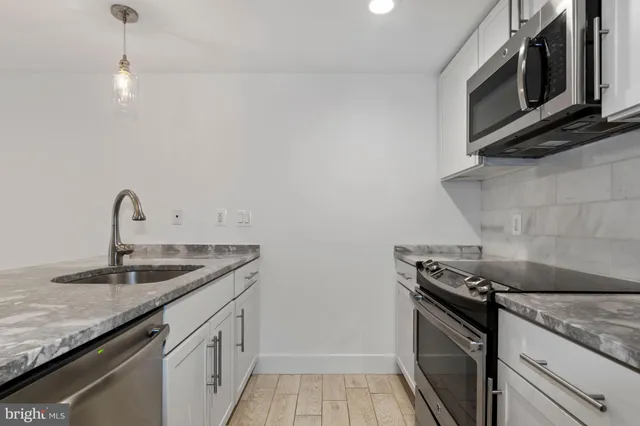 a kitchen with granite countertop a sink stainless steel appliances and cabinets