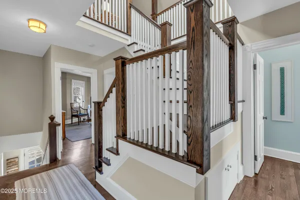 a view of staircase with lots of frames on wall and wooden floor