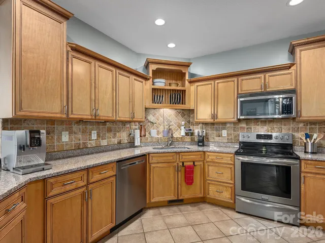 a kitchen with stainless steel appliances granite countertop white cabinets a sink and a stove