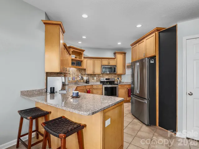 a kitchen with stainless steel appliances granite countertop a refrigerator a stove a sink a dining table and chairs