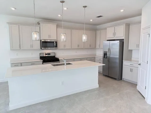 a large kitchen with stainless steel appliances kitchen island a stove a refrigerator a sink a center island and a counter top space