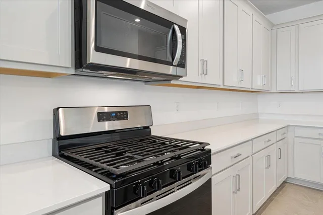 a kitchen with white cabinets and appliances