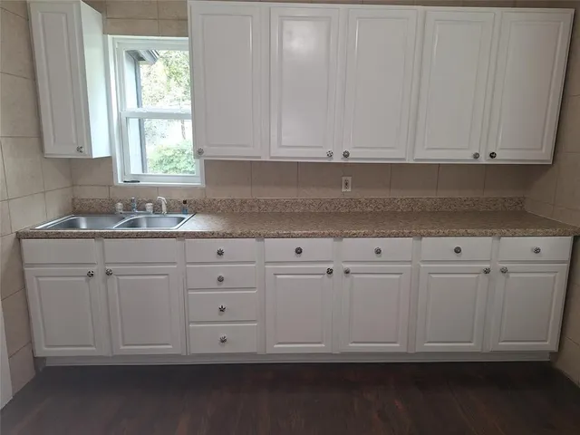 a kitchen with white cabinets and a window