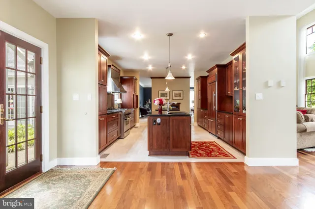 a view of a kitchen with kitchen island granite countertop wooden floor and stainless steel appliances
