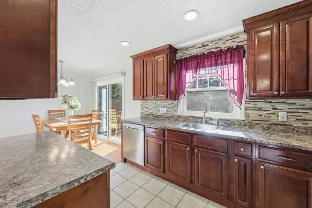 a kitchen with kitchen island granite countertop a sink dishwasher stove and cabinets