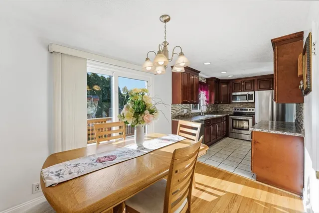 a kitchen with stainless steel appliances granite countertop a stove top oven a sink dishwasher and a dining table with garden view