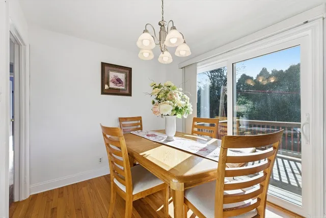 a dining room with wooden floor a chandelier a wooden table and chairs
