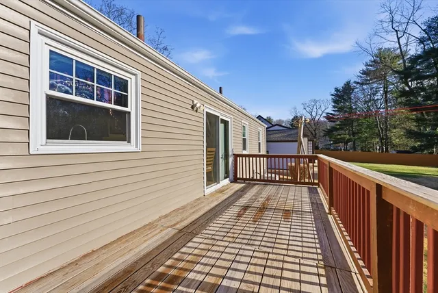 a view of a balcony with wooden floor and large trees