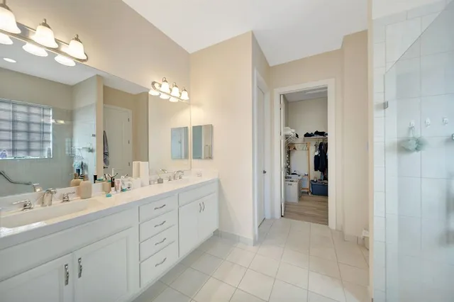 a spacious bathroom with a double vanity sink a large mirror a shower and a bathtub