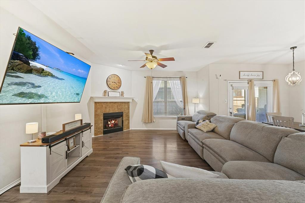 3801 Surf Street Denton, TX 76208 - Photo 9 of 29 Living room featuring dark wood-style floors, a ceiling fan, a tiled fireplace, and suspended lighting