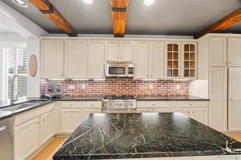 a kitchen with granite countertop a sink a window and cabinets