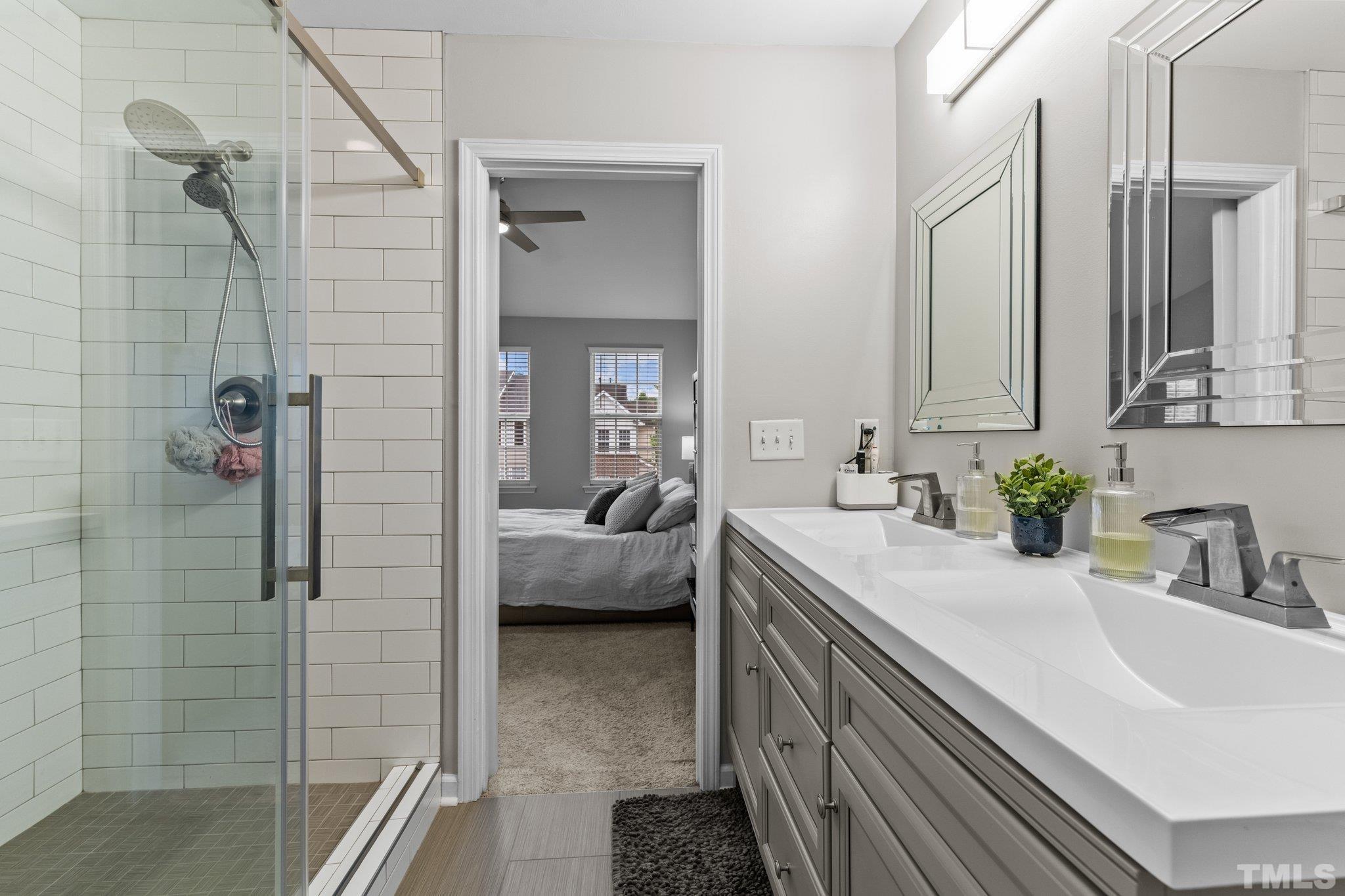 7882 Spungold Street Raleigh, NC 27617 - Photo 14 of 27 a en suite bathroom with a double vanity sink a large mirror and shower