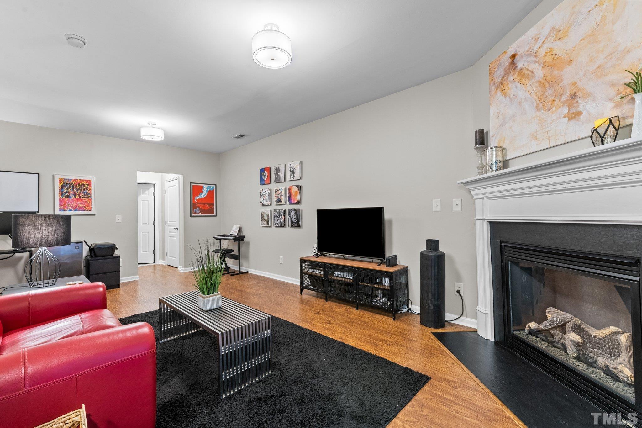 7882 Spungold Street Raleigh, NC 27617 - Photo 18 of 27 a living room with furniture a flat screen tv and a fireplace