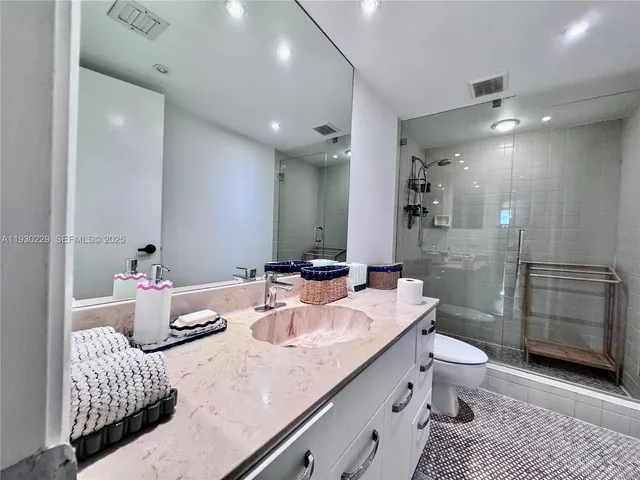 a bathroom with a granite countertop sink a toilet and shower