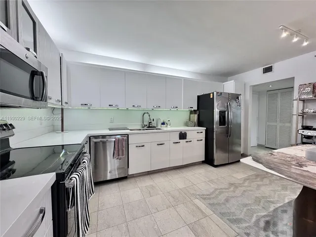 a kitchen with stainless steel appliances a refrigerator sink and cabinets