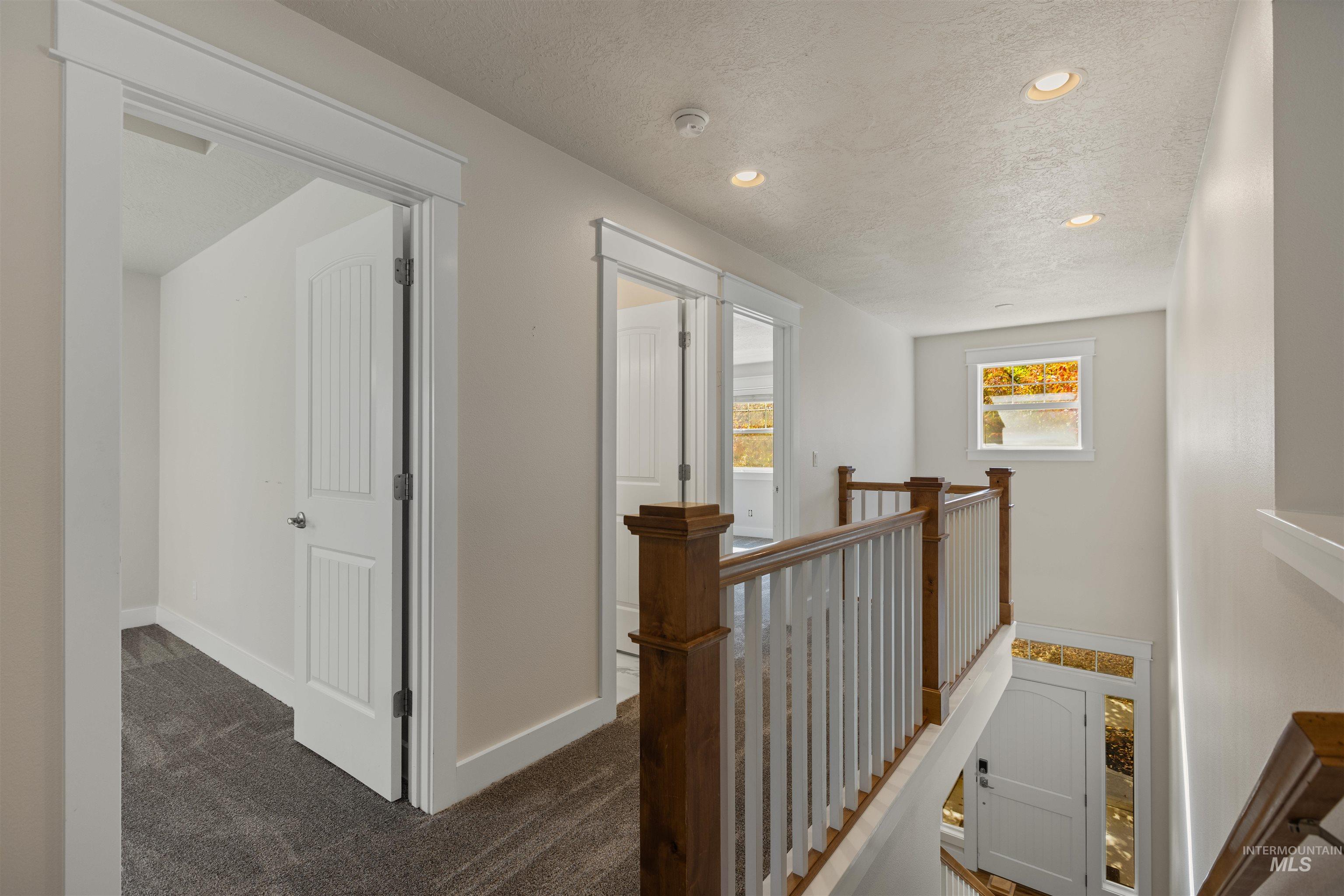 5426 West School Ridge Road Boise, ID 83714 - Photo 36 of 39 White paneled interior doors, recessed ceiling lighting, wood and white baluster railing, and natural light